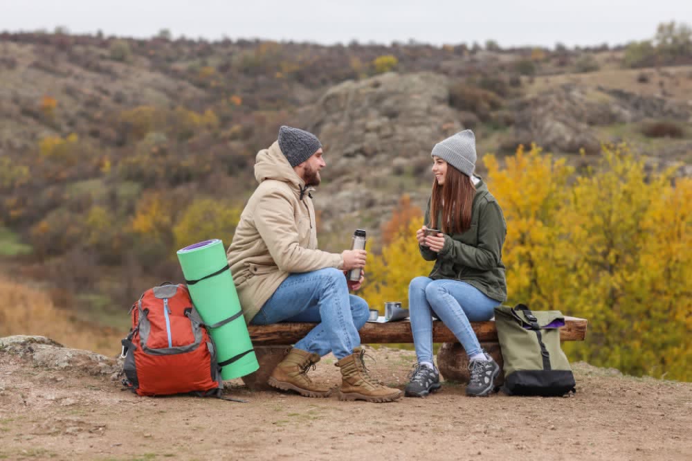 Two walkers chatting over a hot drink on a trail bench