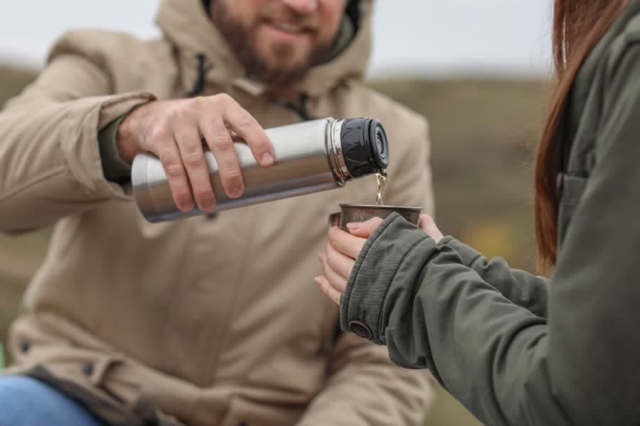 Pouring hot coffee from a thermos on a cold morning walk