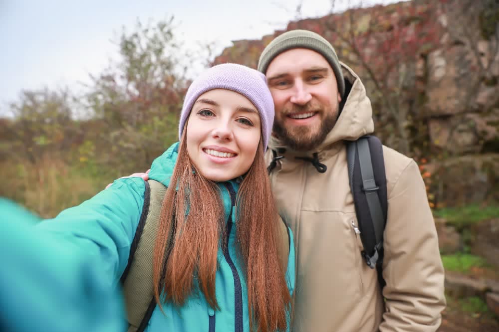 Two smiling walkers taking a selfie on a fall trail